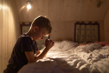 little child boy say a prayer next to bed 