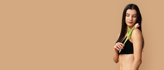 Beautiful young woman in underwear holding tulip flower on beige background with space for text
