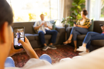 Taking photo with smartphone, person capturing family relaxing on couch