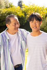 asian father and son smiling together, enjoying quality time outdoors in garden