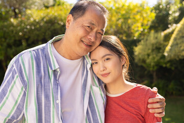 Fototapeta premium Embracing outdoors, smiling asian father and daughter enjoying quality family time together