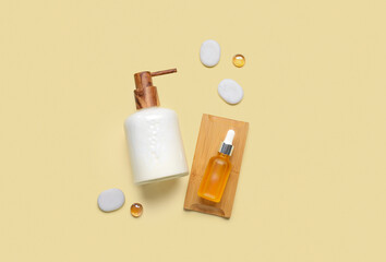 Soap dispenser with stones and bottle of cosmetic oil on orange background