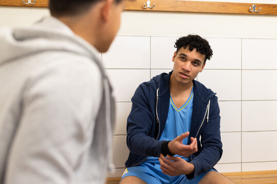 Talking with teammate, basketball player in locker room before game