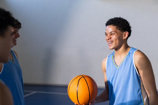 Playing basketball, young men in sports jerseys smiling and holding ball, copy space