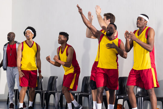 Cheering and celebrating, basketball team in yellow and red uniforms on sidelines