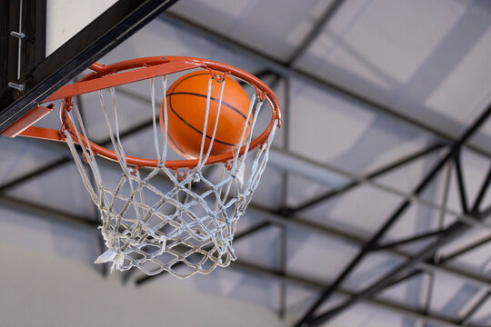 Basketball going through hoop in indoor court during game or practice