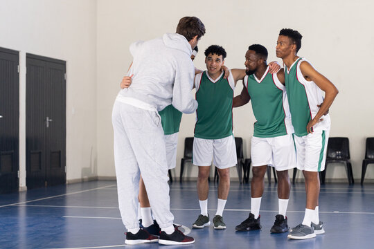 Basketball coach giving pep talk to team players in gym before game