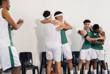 Celebrating victory, basketball team hugging and cheering on court sidelines
