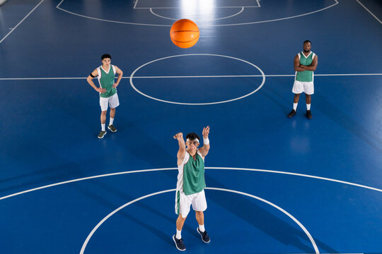 Playing basketball, three players on court practicing shooting and teamwork