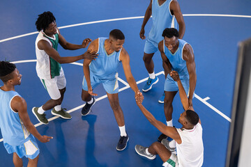 Helping teammate stand up, African American basketball players showing teamwork and sportsmanship on