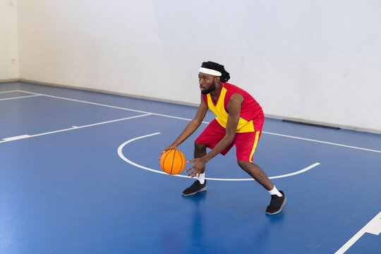 Dribbling basketball on court, man in sportswear practicing basketball skills, copy space
