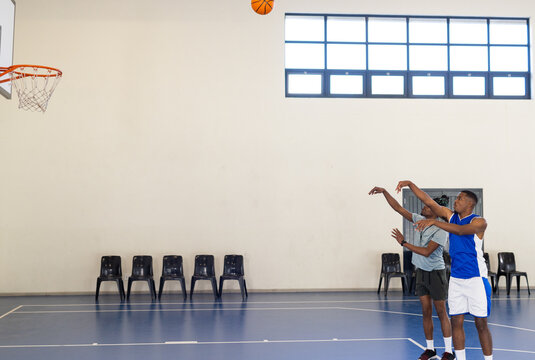 Playing basketball, african american men shooting hoops in court, focusing on technique, copy space