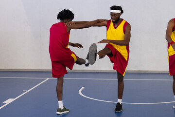Playing basketball, two athletes practicing defensive moves on indoor court