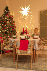 Interior of festive room with Christmas tree, decorations and served dining table at evening