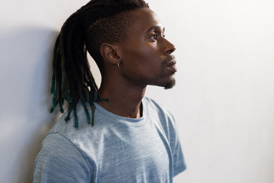 Profile of man with dreadlocks looking thoughtful, wearing casual blue shirt