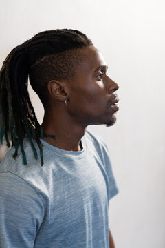 Looking thoughtful, man with dreadlocks wearing blue shirt in profile view