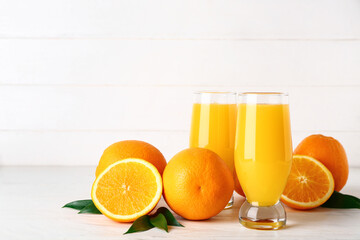 Glasses of fresh orange juice on white wooden background
