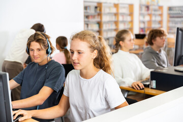 Obraz premium Teenager girls and boys studying in computer lab in library.