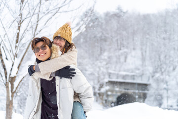 Fototapeta premium Happy young Asian man and woman couple enjoy and fun outdoor lifestyle playing snow together during road trip travel countryside and forest mountain in Japan on winter snow holiday vacation.