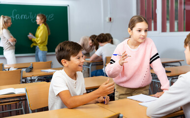Obraz premium Group of diligent school kids discussing something in group during lesson in classroom in secondary school