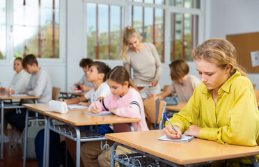 Fototapeta premium Teenage students are sitting at their desks in classroom
