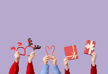 Female hands with Christmas reindeer horns headbands, gift boxes and candy canes on lilac background © Pixel-Shot