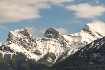Obraz premium Incredible spring time views in Canmore, Alberta during May with Three Sisters Peaks in view with beautiful blue sky background on perfect day. 