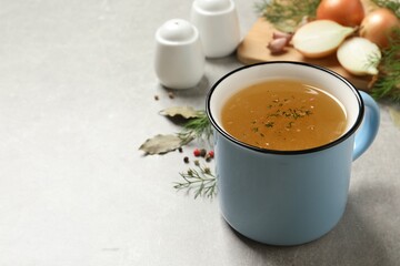 Hot delicious bouillon with dill in cup on light grey table. Space for text