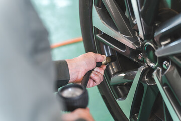 タイヤ空気圧を測定・タイヤに空気を入れる自動車整備士の手元
