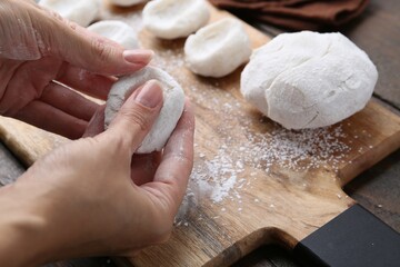 Woman making tasty mochi at wooden table, closeup