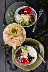 Greek-style Gyro Bowls with Shredded Beef and Oregano: Meal topped with tzatziki, feta, black olives, cucumber, and more served with hummus and pita