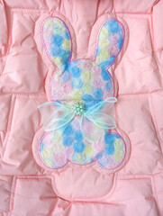Winter cloth. Pink padded jacket with embroidery, cute light blue bunny on back. Art craft. Fashion sherpa coat for cold season