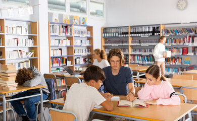 Obraz premium Teenage students working in groups in college library