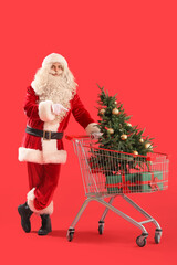 Santa Claus with Christmas tree and gift boxes in shopping cart on red background