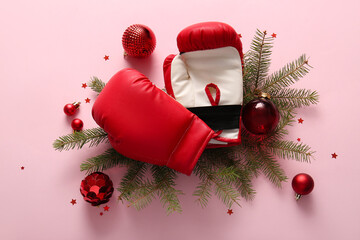 Composition with boxing gloves, Christmas balls and fir branches on pink background