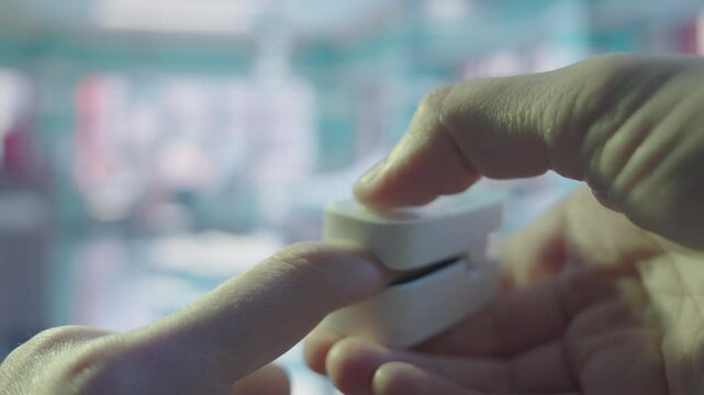Pulse Oximetry in Action: Doctor Placing Oxygen Sensor on Patient's Fingertip | Vital Sign Monitoring in Blurred Hospital Room | Close-up of Medical Device Application