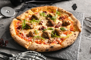 Board of tasty pizza with mushrooms and skeleton hand for Halloween celebration on grey background