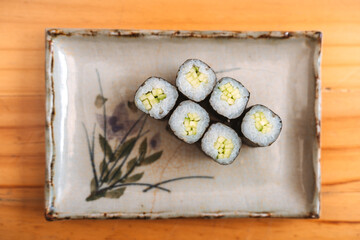 Six pieces of cucumber maki sushi on a decorative plat