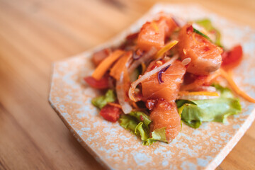 Spicy salmon salad with vegetables on a decorative plate.