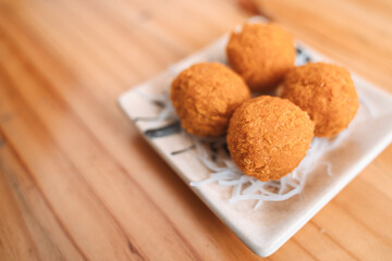Golden crispy croquettes on a ceramic plate with shredded garnish.