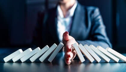 businessman’s hand stops a falling domino, symbolizing control and strategy in a fast-paced environment. The modern table reflects a sleek workspace, highlighting the importance of decisive action in 