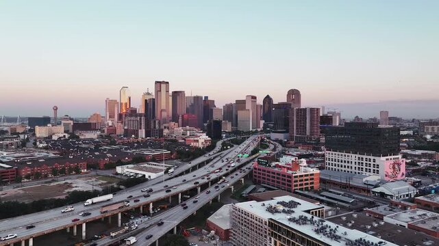 Aerial video of downtown Dallas, Texas during sunrise with highways, traffic and skyscraper buildings in the background.