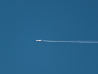 A plane is flying through the sky, leaving a trail of white smoke behind it