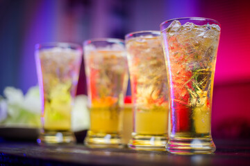 A cold beer glass sits on a cluttered desk during a late-night party, its golden hue reflecting the dim lighting, creating a relaxed atmosphere for unwinding, put on black wooden desk