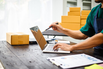 close-up of a man's hands working meticulously with a cardboard box on wooden desk, representing an online seller effort to pack products, successful business operations and customer satisfaction.