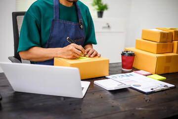 close-up of a man's hands working meticulously with a cardboard box on wooden desk, representing an...