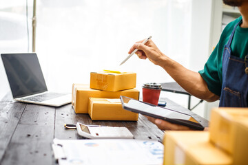 close-up of a man's hands working meticulously with a cardboard box on wooden desk, representing an...