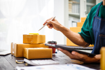 close-up of a man's hands working meticulously with a cardboard box on wooden desk, representing an online seller effort to pack products, successful business operations and customer satisfaction.