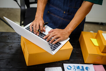 close-up of a man's hands working meticulously with a cardboard box on wooden desk, representing an...