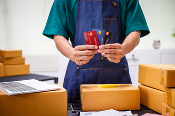 close-up of a man's hands working meticulously with a cardboard box on wooden desk, representing an...